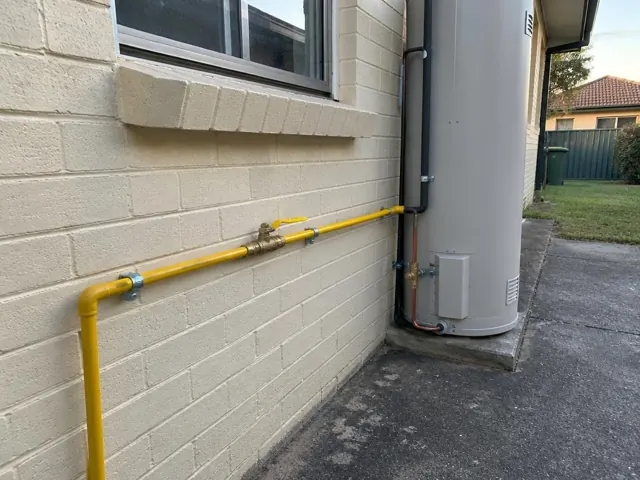 Yellow gas pipe along a brick house wall beside a hot water unit in Rooty Hill